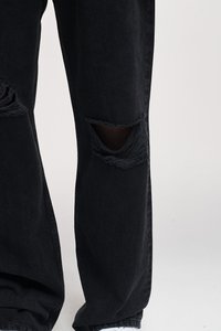 Svarte denim bukser med slitte detaljer, med revne knær, frynsete kanter og en avslappet passform. Glatt tekstur med en matt finish.