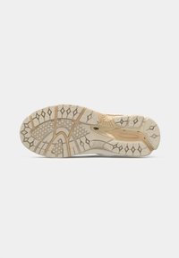 Tread pattern on beige and light brown athletic shoe sole with diamond and grid textures, designed for grip and flexibility.