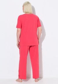 Roze top met korte mouwen en bijpassende broek gemaakt van zachte stof, met een relaxte pasvorm en zijaccenten op de broek.