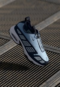 Nike slip-on tenisice u svijetloplavoj i tamnoplavoj boji, s prozračnim mrežastim panelima, zaobljenim vrhom i teksturiranom potplatom s zračnom amortizacijom.
