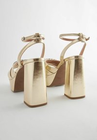 Gold metallic high-heeled sandals with a thick block heel, ankle strap, and an open toe design. Smooth texture and slight platform.