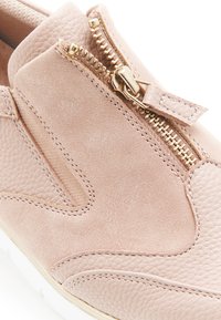 Sneaker in scamosciato e pelle rosa chiaro con dettaglio della cerniera dorata e suola bianca, in primo piano che mostra la parte superiore e le cuciture.