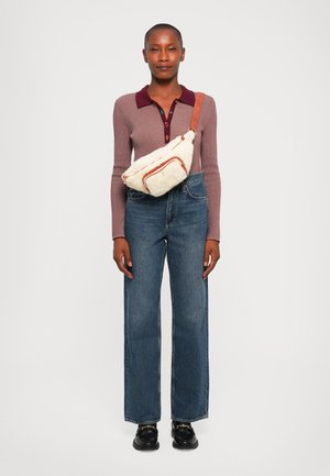 Beige crossover-veske med oransje detaljer, myk tekstur; langermet lilla topp med vinrød krage; vide blå denimjeans; svarte sko.