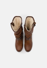 Bottines en cuir marron avec doublure en fourrure, zips sur les côtés et straps décoratifs, avec une finition texturée et un bout arrondi.