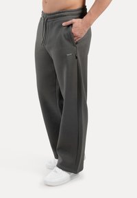 Gray sweatpants with a relaxed fit, elastic waistband, side pockets, and white sneakers. Soft texture and minimal branding detail.