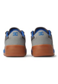 Grijze en blauwe sneakers met een gestructureerde bovenkant, een gevoerde kraag en een oranje rubberen zool. Bevat het logo aan de achterkant in het blauw.