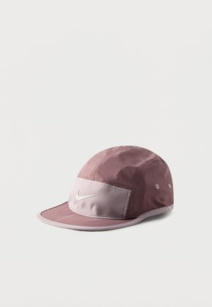 Jasnoróżowa i jasnofioletowa czapka Nike z zakrzywionym daszkiem oraz haftowanym białym logo Swoosh na przedniej części, przedstawiona na jednolitym białym tle.