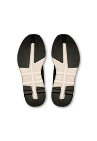 Sorte og hvide sportssko-såler har en struktureret sort gummiydersål og en hvid skummellemsål med markante riller og detaljer.