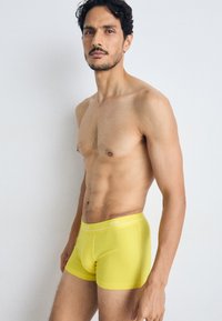 Gule boxerunderbukser med tætsiddende design, der har en hvid logo-elastik, blød tekstur og minimale sømme for komfort.