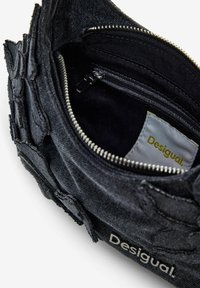 Black denim pouch with textured fabric, silver zipper, interior pocket, and a label featuring the text "Desigual" in yellow.