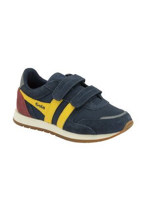 Marineblauwe sneaker met gele strepen, rode hiel, klittenbandsluitingen, witte tussenzool en bruine buitenzool, met het merk "Gola" op de zijkant.