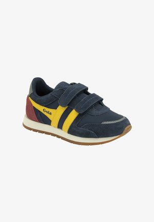 Baskets bleu marine avec des bandes jaunes, un talon rouge, des scratchs Velcro, une semelle intermédiaire blanche et une semelle extérieure marron, estampillées « Gola » sur le côté.