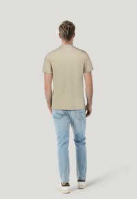 Beige short-sleeve t-shirt, smooth fabric with contrasting collar trim, paired with light blue jeans and white sneakers.