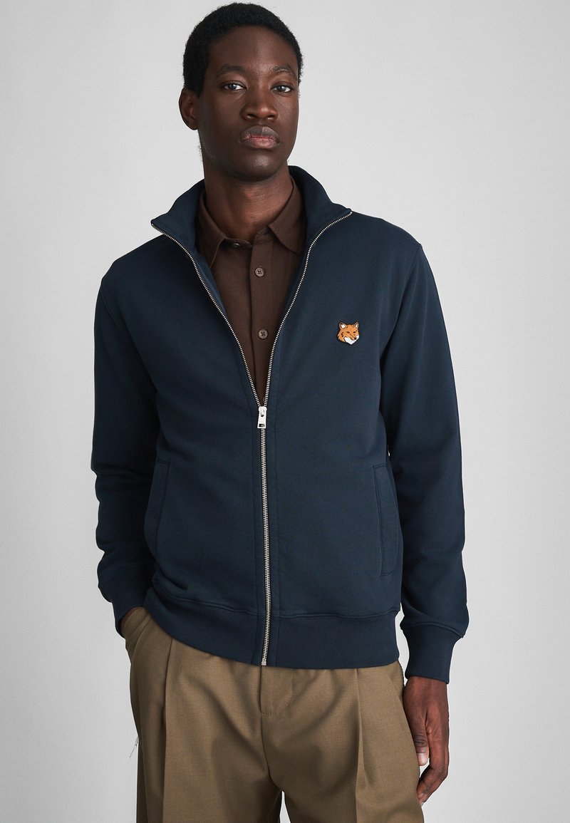 Felpa zip-up blu navy in cotone, con colletto alto, tasche laterali e ricamo a forma di testa di volpe sul lato sinistro del petto.