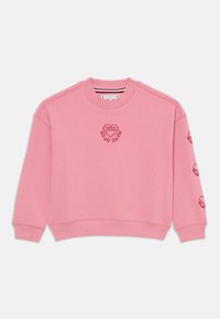 Ružová mikina vyrobená z mäkkej látky, so srdcovým logom "TOMMY HILFIGER" a kvetinovými akcentmi na prednej strane a rukávoch. Rebrované zakončenie a manžety.