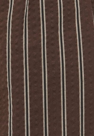 Καφέ ύφασμα με υφή και κάθετες ρίγες σε εκρού και μαύρο. Οι ρίγες είναι ομοιόμορφα διατεταγμένες και έντονα καθορισμένες.