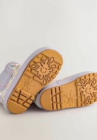 Bunte, gepunktete Schuhe mit einer Lavendelsohle und einer strukturierten Gummisohle, die mit einem Smiley-Gesicht-Design verziert ist. Glatte Oberfläche, niedriges Profil.