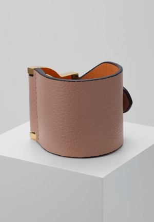 Wide brown leather cuff bracelet with gold metal accents displayed on a white pedestal against a gray background.