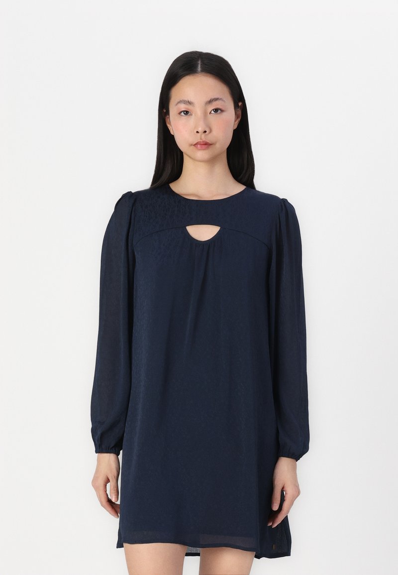 Vestido azul-marinho com mangas bufantes longas, decote redondo e recorte em forma de olho-chave. Feito de tecido leve com uma textura sutil.