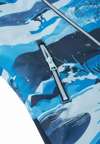 Tela azul y blanca con un diseño ondulado. Presenta un zipper plateado con una lengüeta blanca, sobre una superficie texturada.