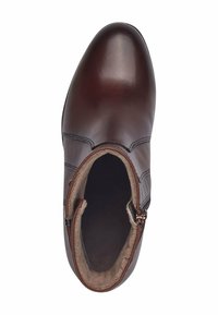 Bota de tobillo de cuero marrón con un acabado suave, que presenta un zipper lateral, un interior forrado de felpa y costuras detalladas a lo largo de los lados.