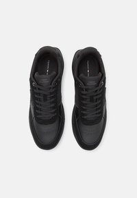Sneakers neri realizzati con una combinazione di materiali in pelle e tessuto. Presentano una punta arrotondata, accenti perforati e lacci piatti.