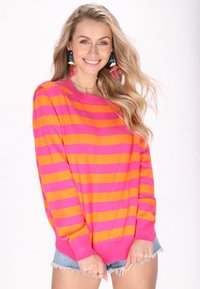 Pulover cu dungi roz și portocalii, cu mâneci lungi și tivuri cu nervuri, asortat cu pantaloni scurți din denim cu margini desfăcute. Detaliu notabil: cercei colorați.