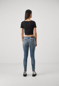 Svart kortärmad t-shirt i kombination med blå skinny jeans. Jeffen har en blekt tvätt och bakfickor. Modellen har på sig klumpiga silverskor.