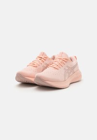Light pink athletic shoes made from mesh material, featuring textured accents, rounded toes, and flat rubber soles with ridges for traction.