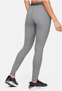 Szare legginsy wykonane z elastycznego materiału z wysokim stanem, zdobione tonalnym logo po bokach i gładką teksturą.
