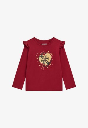 T-shirt a maniche lunghe rossa in cotone con dettagli a volant sulle maniche, un logo a forma di cuore dorato con stelle e il nome del marchio "GUESS" stampato all'interno.