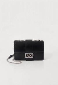 Sort læderhåndtaske med rektangulær form, der har en sølvkæde som rem og en frontlukning med bogstaverne "AX".