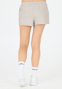 Grå idrottsshorts med en slät textur, med sidofickor och en avslappnad passform. Bärs med vita strumpor och sneakers.