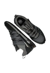 Grijze sportieve schoenen met een bovenwerk van gaas, getextureerde accenten en een zwarte rubberen zool; voorzien van een vetersysteem en een trekband voor gemakkelijk aan- en uittrekken.