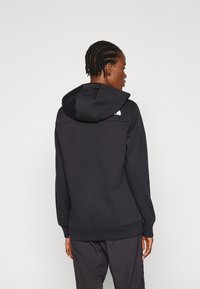 Sudadera con capucha negra de textura suave. Presenta un logotipo en el hombro y puños y dobladillo acanalados para un aspecto ajustado.