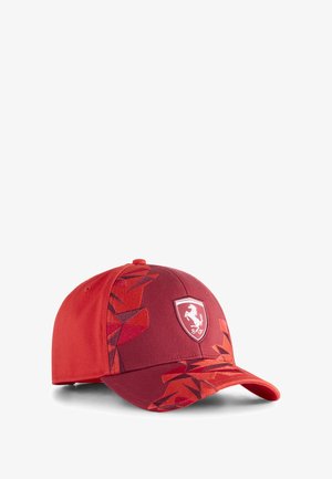 Gorra de béisbol roja con un patrón geométrico texturizado en 3D, con un logo de Ferrari embordado en la parte frontal y visera contrastante.