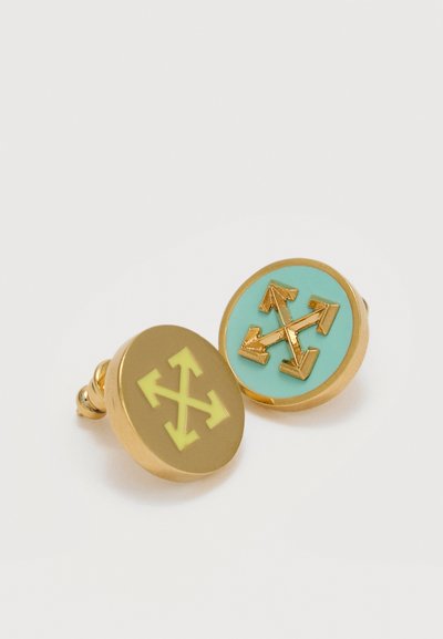 Στρογγυλά χρυσά μανικετόκουμπα με πρόσοψη σε τιρκουάζ και μπεζ χρώμα, καθένα διακοσμημένο με χρυσό σύμβολο σταυρού με τέσσερα βέλη που δείχνουν προς τα έξω.