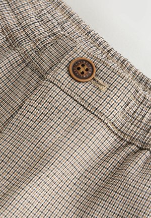 Brunt og cremefarvet mønstret stof med en tekstureret vævning. Har en brun knap og elastik taljebånd øverst.