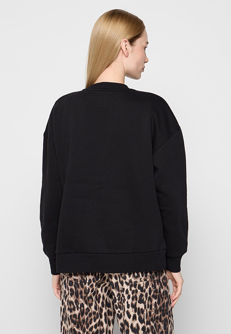 Zwarte sweatshirt met een relaxte pasvorm, geribbelde manchetten en halslijn. De achterkant heeft minimale naad-details, gecombineerd met broek met luipaardprint.