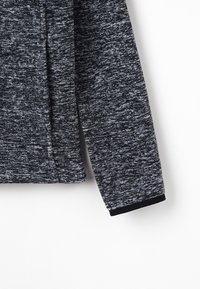 Ciemnoszara, teksturowana bluza z długimi rękawami z melanzowym wzorem oraz czarnymi ściągaczami na dole i przy rękawach.