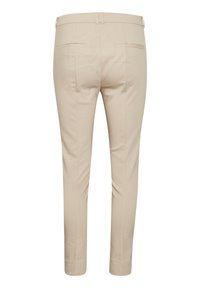 Pantalones beiges ajustados con un corte entallado, que presentan una textura suave, bolsillos traseros y un sutil detalle en las costuras. Sin marcas visibles.