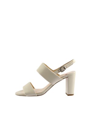 Beżowy sandał na wysokim obcasie, otwarty z przodu, z dwoma szerokimi paskami i regulowanym paskiem wokół kostki z klamrą.