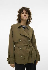 Olivgrön trenchcoat med dubbelknäppt design, bälte i midjan och stora knappar. Har en välvd krage och vida ärmar.