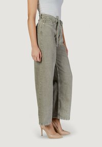 Pantalones beige de pierna ancha y tiro medio con cintura con cinturón. Tejido texturizado con un patrón sutil, con un corte holgado y dobladillos acampanados.