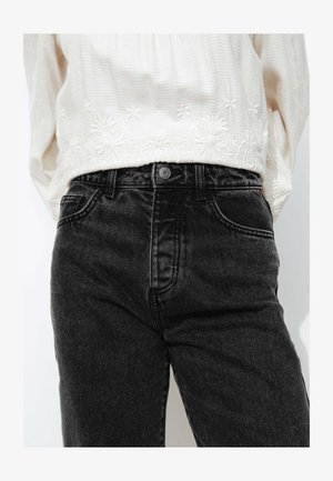 Jeans en denim noir avec une taille haute, dotés de cinq poches et d'une fermeture à bouton. Le tissu a une apparence légèrement texturée.