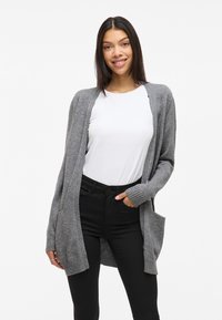 Gray knit cardigan with open front, ribbed cuffs, and two front pockets, paired with a white shirt and black pants. Smooth texture.