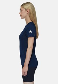 Mörkblå atletisk t-shirt med korta ärmar, figursydd design och textilerad struktur. Har en rund halsringning och en logotyp på vänster ärm.