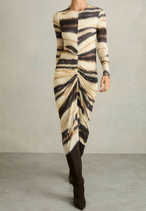 Vestido midi de manga larga con fruncidos y patrón de rayas de tigre en beige, negro y marrón, combinado con botas negras hasta la rodilla.