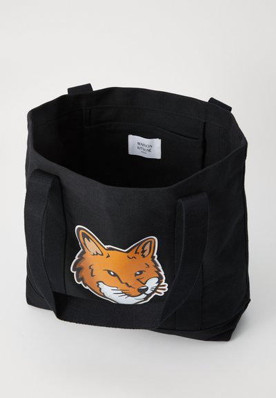 Sac fourre-tout noir en toile avec de solides poignées et un graphisme de renard orange sur le devant. Comprend une étiquette à l'intérieur qui indique "Maison Kitsuné, Paris."