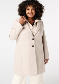 Beige wollen mix coat met een capuchon, voorzien van een sluiting met twee knopen en zijzakken. De binnenkant heeft een lichtgekleurde, gewatteerde voering.